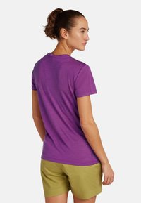 Paarse T-shirt met korte mouwen van zachte stof, met een ronde halslijn en een relaxte pasvorm, gecombineerd met groene shorts.