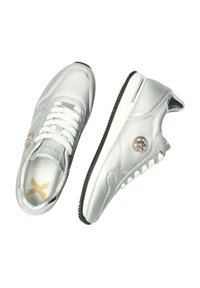 Silberne synthetische Sneakers mit einer strukturierten Oberfläche, Schnürverschluss, schwarzer Sohle und einem kreisförmigen Logo an der Seite. Goldene Akzente auf der Innensohle.