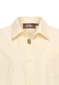 Crème-kleurig shirt met een klassieke kraag, voorzien van een bloemenaccent broche en een klein zakje met geborduurde details.