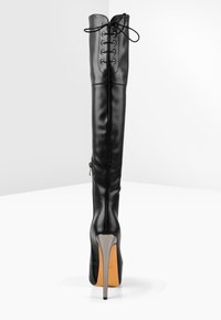 Černé vysoké kozačky z hladké kůže s šněrováním, elegantním designem, špičatou špičkou a vysokým jehlovým podpatkem.