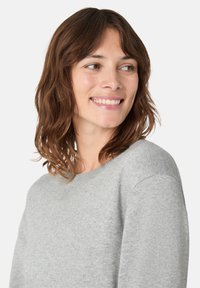 Světle šedý pletený svetr s kulatým výstřihem a dlouhými rukávy. Měkká textura, minimalistický design a žebrované detaily na výstřihu a manžetách.