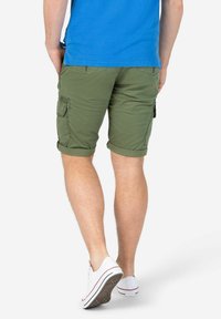 Grüne Cargo-Shorts mit umgeschlagenem Saum, ausgestattet mit zwei seitlichen Cargo-Taschen und Rücktaschen. Kombiniert mit weißen Sneakers.