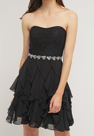 Czarna sukienka bez ramiączek z koronkowym gorsetem, falbaną na spódnicy oraz srebrnym, zdobionym paskiem w talii. Tkanina jest lekka i zwiewna.