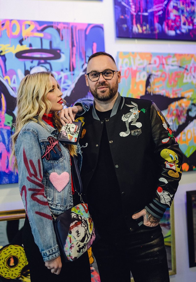 Denim jacket with embroidered details, including a heart and "love." Black bomber jacket with colorful cartoon patches. Printed crossbody bag.