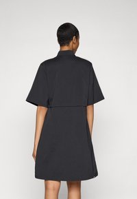 Abito nero a maniche corte con design colletto, vestibilità rilassata e orlo posteriore più corto, realizzato in tessuto leggero. Senza motivi rilevanti.