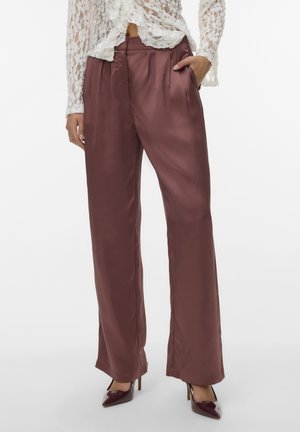 Satijnen, bordeauxrode wijde broek met plooien, zijzakken en een gladde textuur. Gecombineerd met puntige donkerrode hakken.