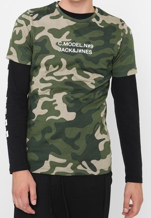 T-shirt camouflage aux tons verts avec un col rond, imprimé en blanc du texte « C.MODEL.N#9 JACK&J#NES » sur le devant. Manches courtes, coupe régulière.
