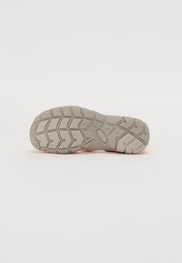 Grå sneakersåle med et strukturert gummimønster og hevede sektioner for grep. Har merkelappen "ikke-merke".