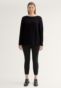 Czarny dzianinowy sweter z długimi rękawami, okrągłym dekoltem i prążkowaną teksturą, zestawiony z czarnymi spodniami slim-fit i czarnymi sznurowanymi butami.