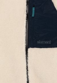 Fleecejacke mit beigem Stoff, navyblauem Materialeinsatz, kontrastierenden Reißverschlüssen und dem in Navy gestickten Markennamen "Element".