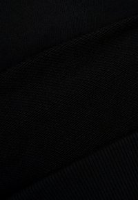 Czarna tkanina w zbliżeniu, pokazująca teksturowane dzianiny i prążkowane sekcje. Materiał jest gładki, z lekkim połyskiem i jednolitą barwą.