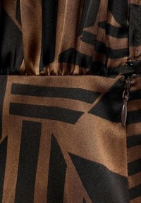 Bruin en zwart patroonstof met geometrische vormen, met een geplooide taille en een ritsdetail. Zachte textuur met een satijnen afwerking.