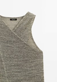 Graues, gestricktes ärmelloses Oberteil mit V-Ausschnitt, das aus einem strukturierten, leicht melierten Stoff besteht und einen klaren, modernen Schnitt aufweist.