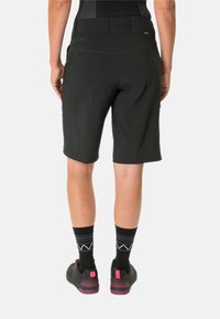 Pantalones cortos negros hechos de un material ligero, con una cinturilla plana, corte a la altura de la rodilla y sin bolsillos visibles, exhibidos desde la parte trasera.