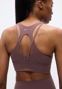 Μωβ αθλητικό σουτιέν με σχεδιασμό racerback, με κοψίματα και μικρό λογότυπο στο πίσω μέρος, κατασκευασμένο από ελαστικό ύφασμα.