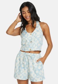 Korte, mouwloze top en shorts met elastische tailleband in lichtblauw met een geometrisch palmenbladpatroon; knoopdetail op de top.