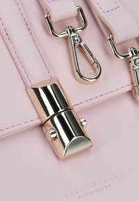 Borsa a mano in pelle rosa con una chiusura e accessori in oro lucido, con dettagli cuciti e nome del marchio impresso sul davanti.