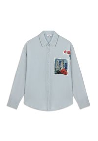 Camicia button-up azzurro chiaro con colletto, caratterizzata da una toppa floreale sulla tasca anteriore e disegni di fiori colorati sulla spalla.