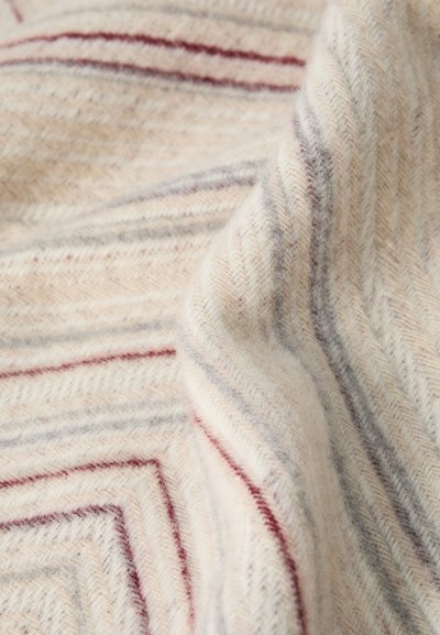 Tift de lână în model herringbone cu o bază crem și dungi roșii și gri, creând un design texturat și cu model. Apariție moale și caldă.