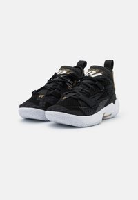 Černé sportovní boty s texturou z prodyšné tkaniny, s zlatými akcenty a bílými gumovými podrážkami. Šněrovací design s polstrovanou podporou kotníku.