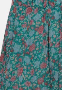 Tela con estampado floral sobre fondo teal, con flores rojas y rosas. Material ligero y texturizado con pliegues que crean interés visual.