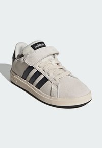 Lichtbeige suède sneaker met zwart drie-strepenontwerp, veter- en klittenbandsluiting, gestructureerde tong en rubberen zool.