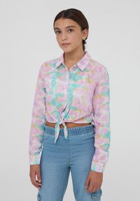 Blusa colorata con maniche lunghe e allacciatura frontale, realizzata in tessuto trasparente con un motivo acquerellato pastello nei toni del rosa, verde e blu. Collo con bottoni.