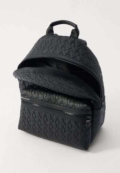 Un sac à dos noir en matériau synthétique texturé qui présente des doubles fermetures éclair, un motif de logo en relief et une poignée supérieure pour le transport.