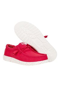 Scarpe di tela rosse con punta arrotondata, suola in gomma maculata bianca e lacci abbinate. L'interno presenta un motivo a zigzag.