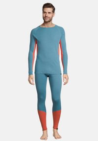 Långärmad thermaltröja och leggings i teal med korallfärgade detaljer på sidorna. Tyget är texturerat, perfekt för layering i kallt väder.
