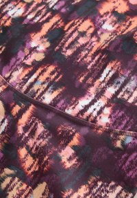 Tela multicolor con un patrón audaz de pinceladas en tonos morado, naranja y verde, con una textura suave y bordes cosidos.