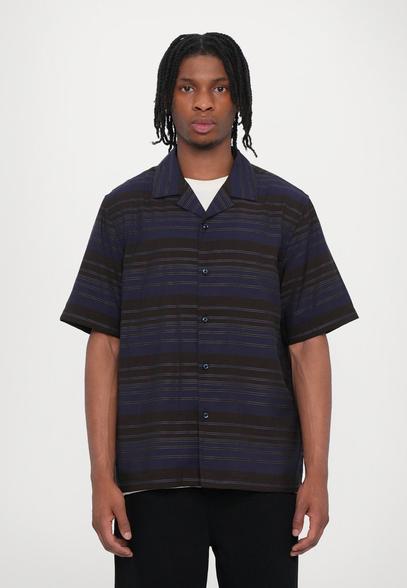 Chemise à manches courtes, col, de couleurs foncées avec des rayures horizontales en bleu et jaune. Fermeture à boutons avec une coupe décontractée et un tissu doux.