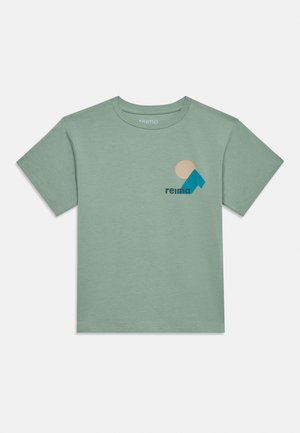 Lichtgroen T-shirt met korte mouwen en ronde hals, met een beige cirkel en een blauwe geometrische vorm naast de tekst "reima" op de borst.