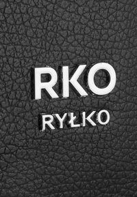 Zwart gestructureerd leer met verhoogde letters "RKO" en "RYŁKO" in zilver, wat een contrasterend designelement creëert.