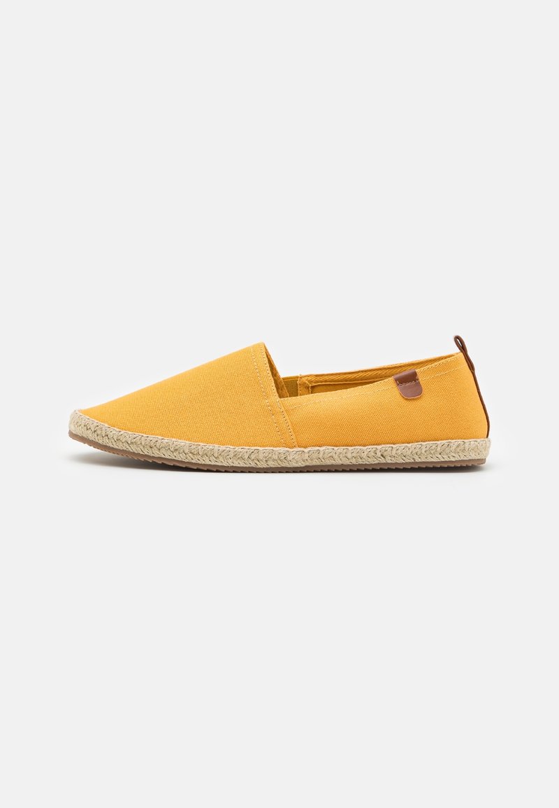 Chaussure espadrille jaune en toile à enfiler avec semelle en jute tressée et petite languette marron au talon, sur fond uni.