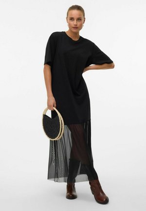 Black t-shirt dress with short sleeves, featuring a sheer black skirt overlay. Paired with a round, woven black bag and brown ankle boots.