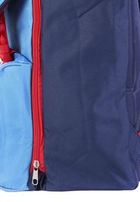 Backpack in blue and navy fabric with red zipper; features a side pocket and textured surface; compact and rectangular shape.