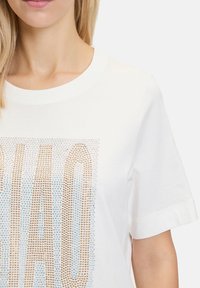 Hvid bomulds-T-shirt med en struktureret design og rhinsten, der staver "CIAO" i guld- og blå nuancer, korte ærmer og rund halsudskæring.