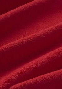 Tissu rouge avec un tissage texturé, présenté en plis doux et sous un éclairage uniforme.