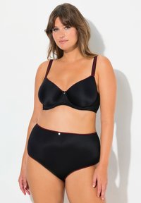 Černá síťovaná podprsenka a sada kalhotek s vysokým pasem, zdobená červenými detaily, s podporou kostic a dekorativním středovým prvkem na podprsence.