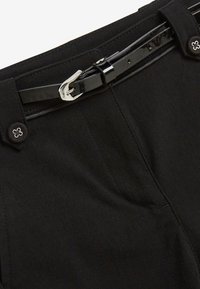 Pantaloni neri con una cintura nera lucida, caratterizzata da una fibbia argentata e bottoni decorativi con un design floreale, tessuto testurizzato.