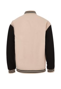 Giacca beige e nera con colletto, maniche a contrasto e polsini e orlo a righe. Texture liscia, design casual.