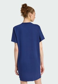 Námornícky modré šaty s krátkymi rukávmi vyrobené z mäkkej tkaniny, s rovnými líniami, okrúhlym výstrihom a mierne predĺženým zadným lemom.