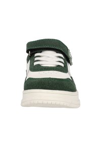 Zapatilla verde de fieltro con acentos de cuero blanco, que cuenta con una cinta de velcro, puntera redonda y suela texturizada para agarre. Los cordones son blancos.