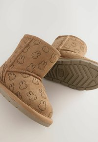 Tan mocka ankelstövlar med kaninmönster, som har en gummisula och sömdekor. Kännetecknas av sin mjuka textur och lekfulla design.