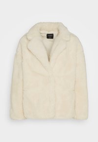 Veste en fausse fourrure couleur crème avec col large et manches longues, étiquetée Lindex, présentée sur fond blanc.
