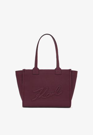 Burgunderfarget lær tote bag med teksturert finish, med doble håndtak og preget "Karl"-logo på forsiden. Åpen toppdesign, minimalistisk stil.