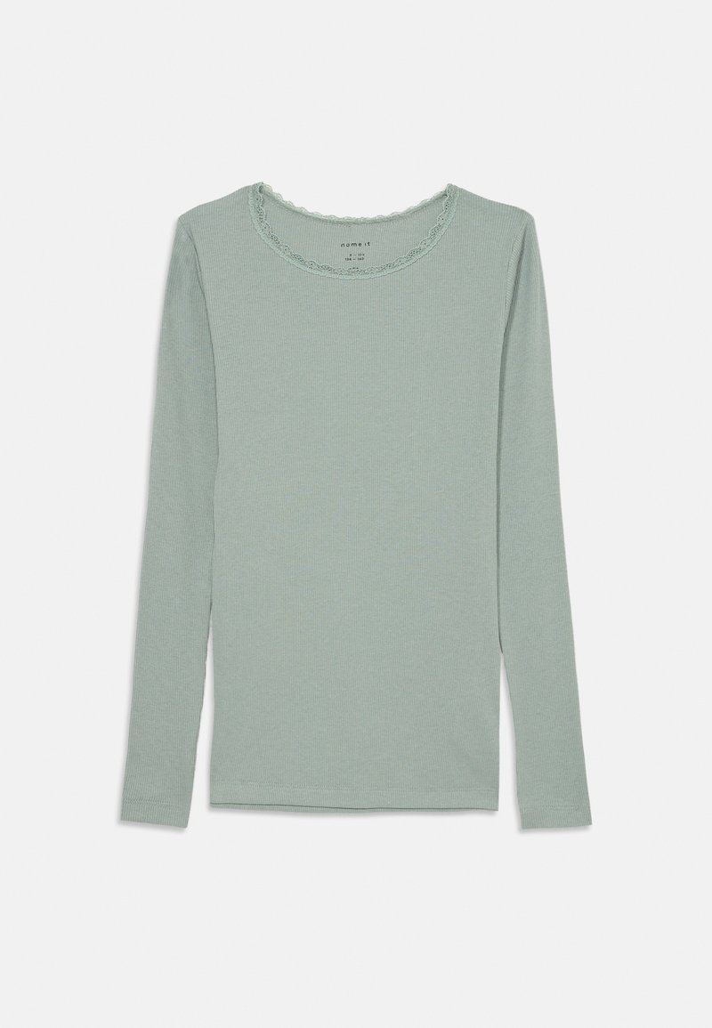 Šviesiai žalia ilgomis rankovėmis palaidinė su vagotomis tekstūromis, apvaliu iškirpimu, puoštu nėriniais, ir prigludusiu siluetu.