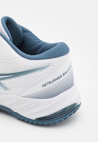 Weißer Sportschuh mit strukturiertem Mesh-Obermaterial, hellblauen Akzenten und gepolsterter Zunge. Merkmale sind der Aufdruck "NETBURNER BALLISTIC" und das FlyteFoam-Logo.