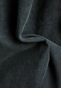 Tissu en velours côtelé gris foncé avec des côtes verticales, une texture douce et un léger éclat. Le matériau est plié, créant des courbes lisses et un tombé naturel.